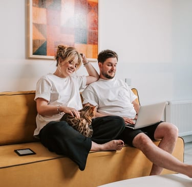 A couple sitting on sofa with their cat and reading about cat vomiting with no other symptoms on the