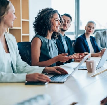 a group of business people sitting at a table with laptops