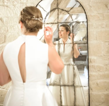 a woman in a white dress is looking at herself in the mirror