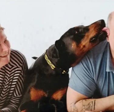 Cheeky Loki our Doberman in a batman collar gives mark a big ear lick while Claire laughs-just another day at collar Rack HQ