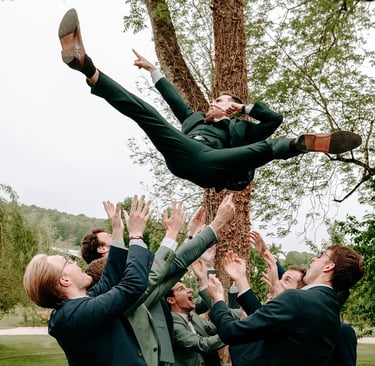 les garçons d'honneur font sauter le marié pendant le vin d'honneur