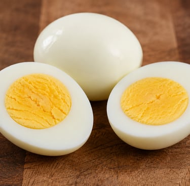 Hard-boiled eggs peeled and sliced in half on a wooden cutting board, showing the cooked yellow yolks.