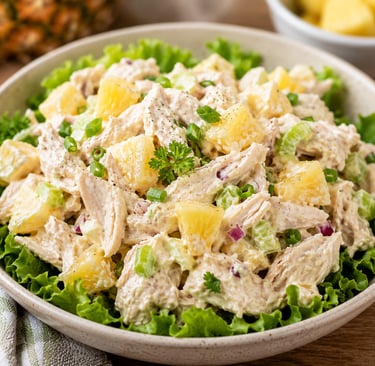 A creamy chicken salad with pineapple chunks, celery, and green onions served on a bed of fresh lettuce.