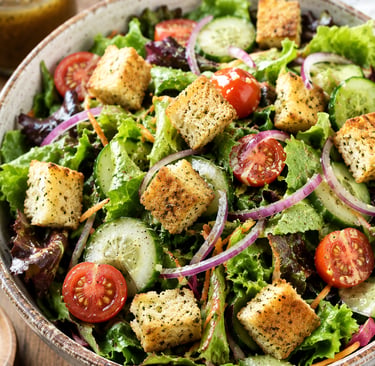 Fresh garden salad with crunchy croutons, cherry tomatoes, cucumbers, and red onion in a bowl.