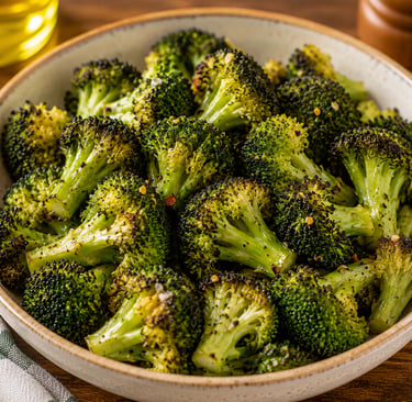A bowl of seasoned roasted broccoli florets with charred edges on a wooden table.