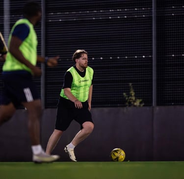 a man in a yellow vest and black shorts playing soccer