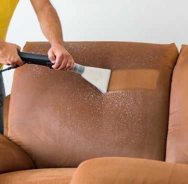 a man cleaning a couch with a vacuum cleaner