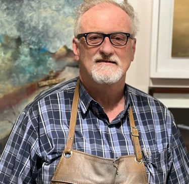 Portrait of Simon Shone, South African sculptor and master goldsmith, wearing a leather apron in his studio