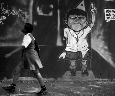 Schoolgirl passing a graffiti wall, from Martin Osner’s “On the Move” collection.