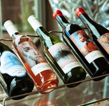 A rack of five Bloupunt wines on a glass table displaying Martin and Samantha Osner's art labels