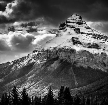 Charity Mountain in the Canadian Rocky Mountains, showcasing it's rugged snow covering and a dramtic sky