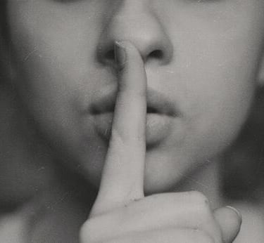 Woman with her forefinger over her lips indicating silence