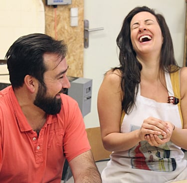 a man and woman laughing while making pottery