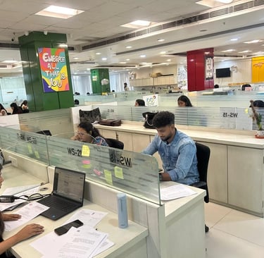 Diverse employees working at desks in a modern open-plan office workspace with laptop computers 