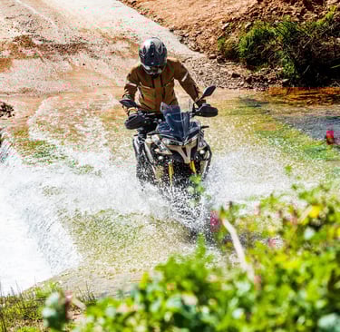 vyras, važiuojantis motociklu per vandens srovę