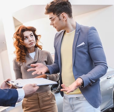a man and woman perplexed in a car dealership