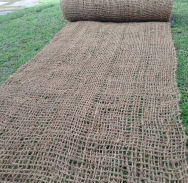 A natural jute garden erosion control mat unrolled on a green lawn, showcasing its eco-friendly mesh