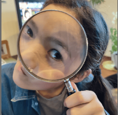 a girl peeping through a magnifying glass