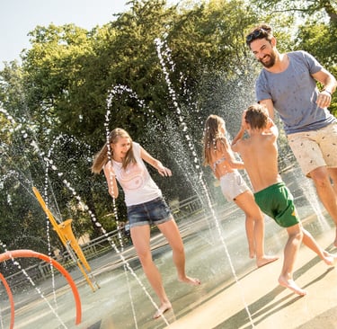 a man and two children playing in a fountain