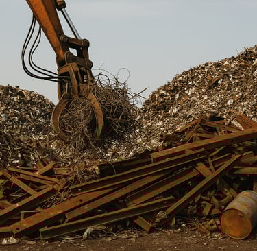  A scrapyard densely filled with rusted scrap metal, featuring an excavator gripping tangled debris 