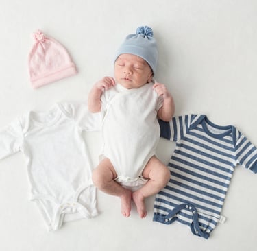Soft natural light illuminating a basket filled with newborn clothing in earth tones.
