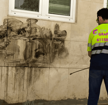 Profesional de Sin Graffitis eliminando graffiti de una fachada con equipo especializado
