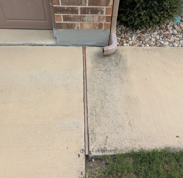 Before Picture of a sidewalk with a gutter downspout that stained the concrete.