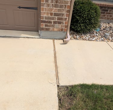 Picture of the cleaned sidewalk with the stain from the gutter downspout removed.  Ponder TX
