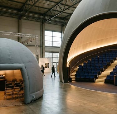 Small portable inflatable dome beside a large fixed planetarium theatre, size comparison.