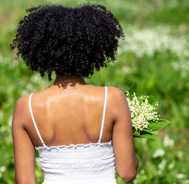 Black woman holding lily of the valley flowers