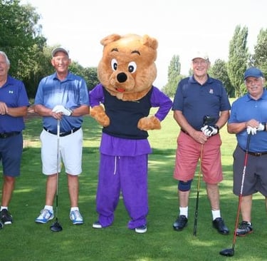 a group of people standing around a bear mascot