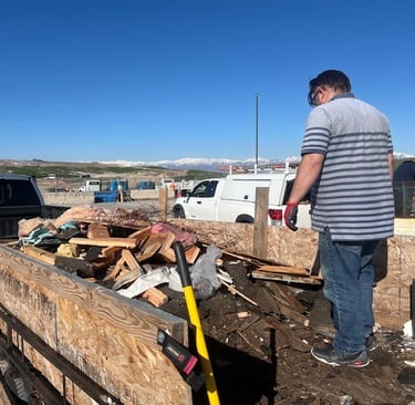 a man standing in trailer emptying it at the dump with a truck in the back