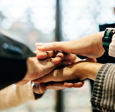 A diverse group of business colleagues stacking their hands together. Photo Credit: Rawpixel Ltd.