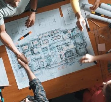 home builders and customer looking over blueprints for new home