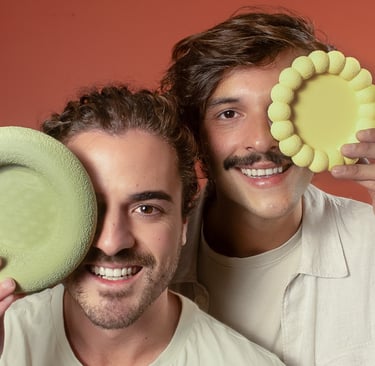 Daniel e Filipe, fundadores da Tidu Home, segurando objetos decoratios em 3D.