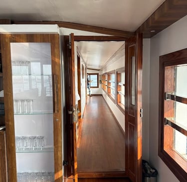 A luxury Alleppey houseboat featuring a furnished  deck, floating on a narrow canal r