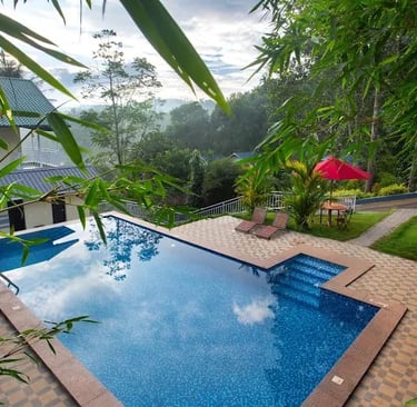 A infinity pool overlooking the rolling green tea plantations at a  Deluxe Hotel in Kerala
