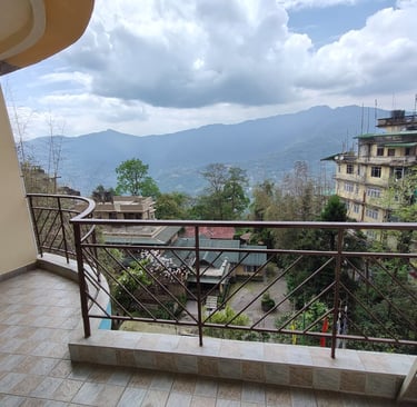 A cozy hotel room in Gangtok with a private balcony that opens up to a  a panoramic view 