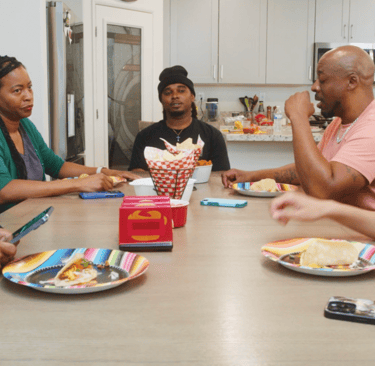 characters Eric, Tasha, Darrell, Sam, Amanda at kitchen table