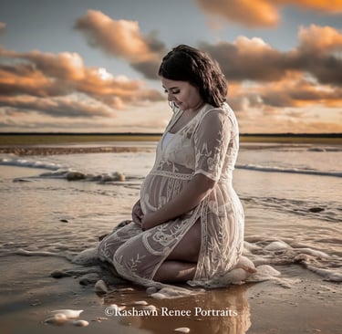 a pregnant woman sitting on the beach in a white dress