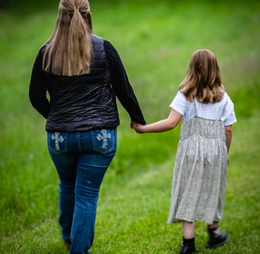 Woman and child holding hands while walking in a grassy field. Glouster_Ohio.jpg