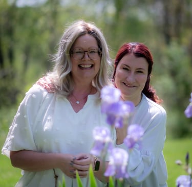 Two smiling women posing together outdoors behind purple iris flowers. sister_Athens_Ohio.jpg