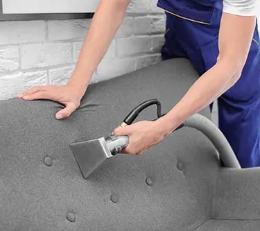 a person cleaning a couch with a vacuum