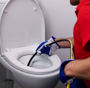 plumber sucking water out of a toilet with a hose