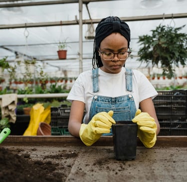 Black girl at potting table in a greenhouse. 