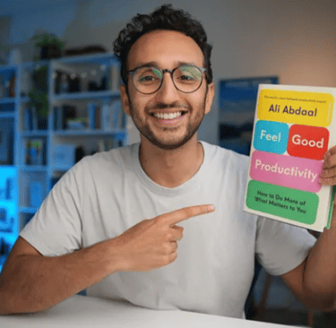 Ali Abdaal holding his book 'Feel Good Productivity'