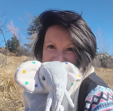 jeune femme souriant presentant une petite peluche elephant