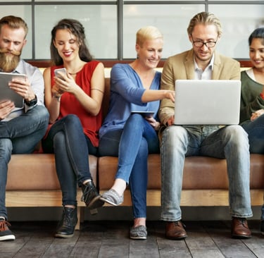 A welcoming community center with diverse people engaging around computers and digital devices.