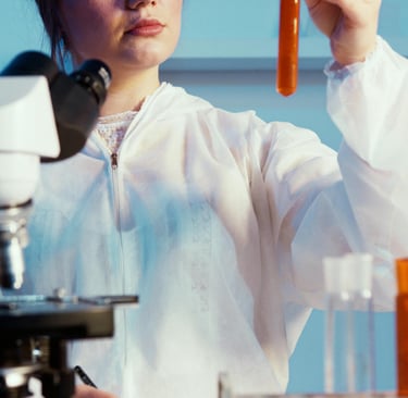 a woman in a lab coat and goggles holding a test tube