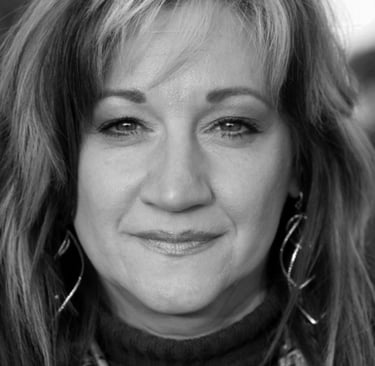 A black and white photo of a middle-aged Caucasian woman with long layered hair
